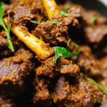 Authentic Beef Rendang recipe served in a traditional bowl with coconut rice and pickled vegetables, showcasing the rich colors and spices of Indonesian cuisine.