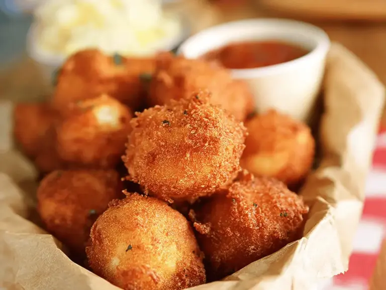 Crispy Sweet Onion Hush Puppies served with dipping sauce, perfect for summer cookouts.