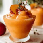 Refreshing Frozen Peach Rosé Slushy in a clear glass with peach slices and mint, perfect for summer parties.